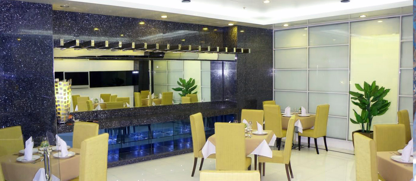 Elegant dining room interior with dark speckled walls, a mirrored panel, yellow upholstered chairs, and white tablecloths